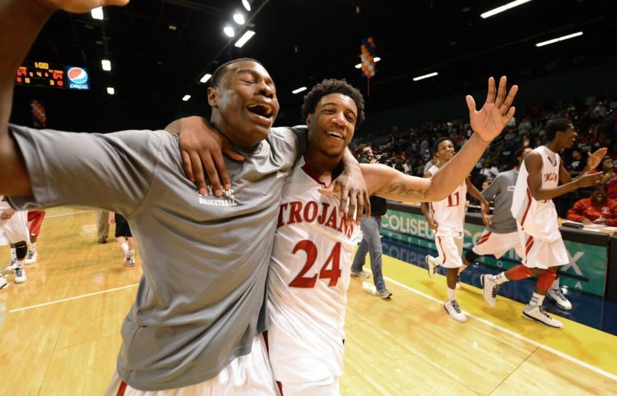 Olympic Trojans star BJ Gladden (24) and a teammate celebrate their victory in the 2013 N.C. 4A Western Regional basketball championship. Olympic defeated Mount Tabor 69-64 en route to winning the school’s first state title.