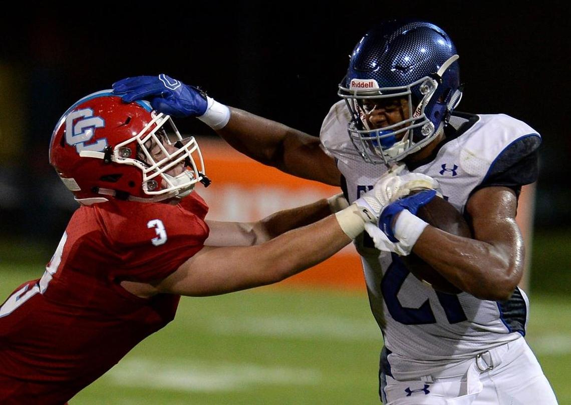 Charlotte Christian's Justus Woods, right, fights for extra yardage as Charlotte Catholic's Jim Hurney, left, tries to make the tackle.