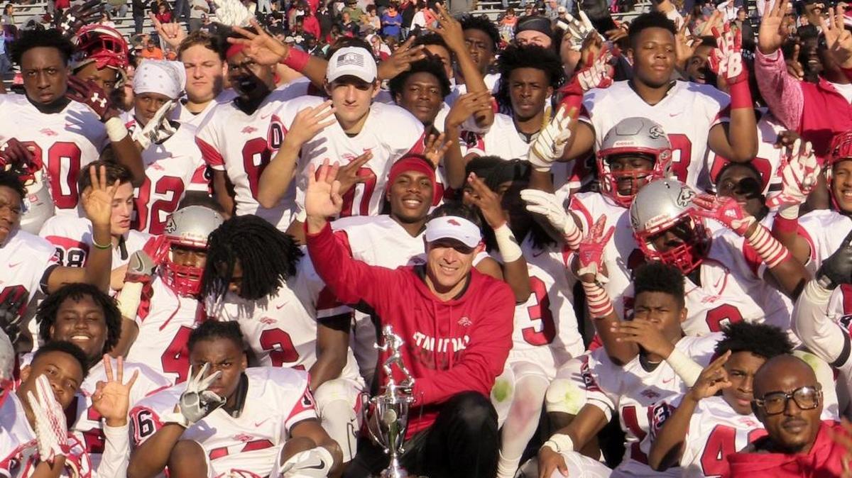 South Pointe varsity football coach Strait Herron, center, poses with his team Saturday after winning the 4A state championship in December.