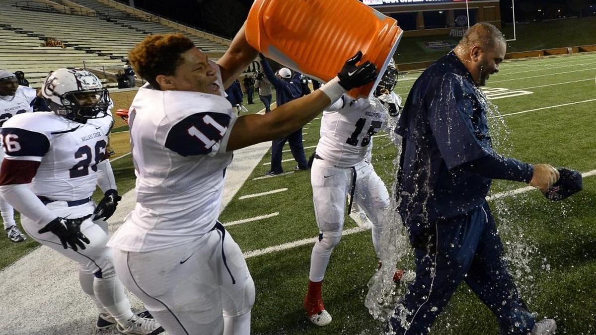 Mallard Creek Mavericks defensive lineman Jonathan Neal (11) dumps a cooler of water on head coach Mike Palmieri as the team celebrated their 25-14 victory over the Wake Forest Cougars in the NCHSAA 4AA State Championship game at BB&T Field at Wake Forest University in Winston-Salem, NC on Saturday, December 13, 2014.