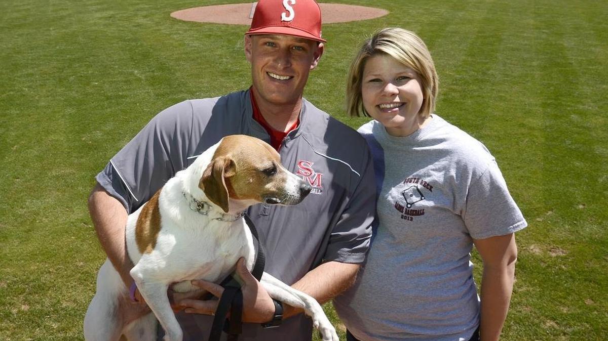 Jon Tuscan, holding his dog, Mick, and his wife Sarah Tuscan are expecting their first child in late May. The couple and their pet posed for a portrait on Friday, April 24, 2015 at South Meck's baseball field. Two years after winning the state championship, South Meck baseball coach Jon Tuscan is two years clear of having his testicular cancer go into remission, a period where doctors say he is out of the woods. His baseball team is again in the hunt for states, playing rival Providence Tuesday. He was diagnosed after his dog, Mick, jumped his lap with such ferocity that he went to the doctor for pain. That canine leap saved his life.
