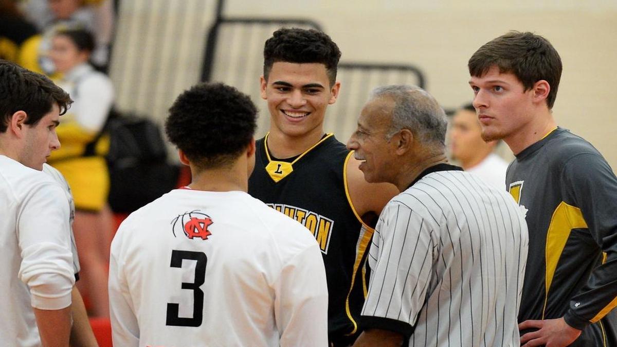 Lincolnton High basketball star Sage Surratt (center) cracks a smile during a referee’s pregame instructions last week at Newton-Conover. Surratt, a two-sport standout, was recently name the state’s top offensive football player. In basketball, he’s the country’s third-leading scorer, averaging 36.9 points.