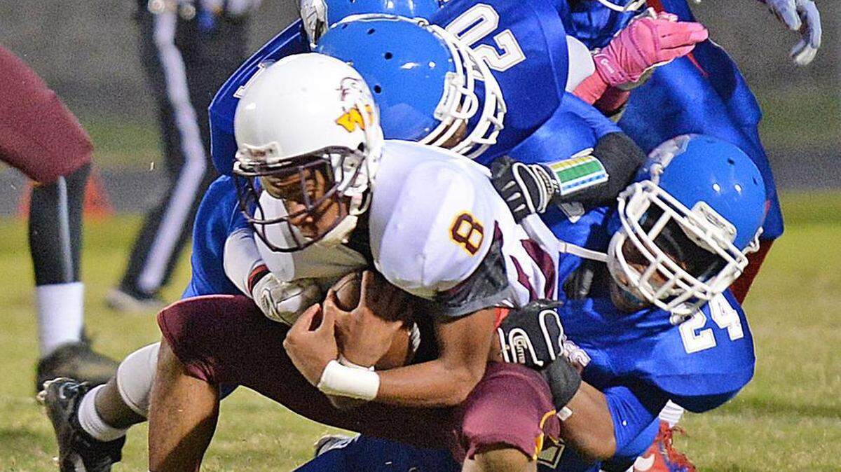 
North Meck’s Branden Payne and other defenders keep West Charlotte receiver Dezmien Berry (8) from picking up more yardage during Thursday’s game at North Mecklenburg. The host Vikings won, 32-25. The game was one of 10 in the Observer’s coverage area that were moved up a day because of the threat of severe weather. 
