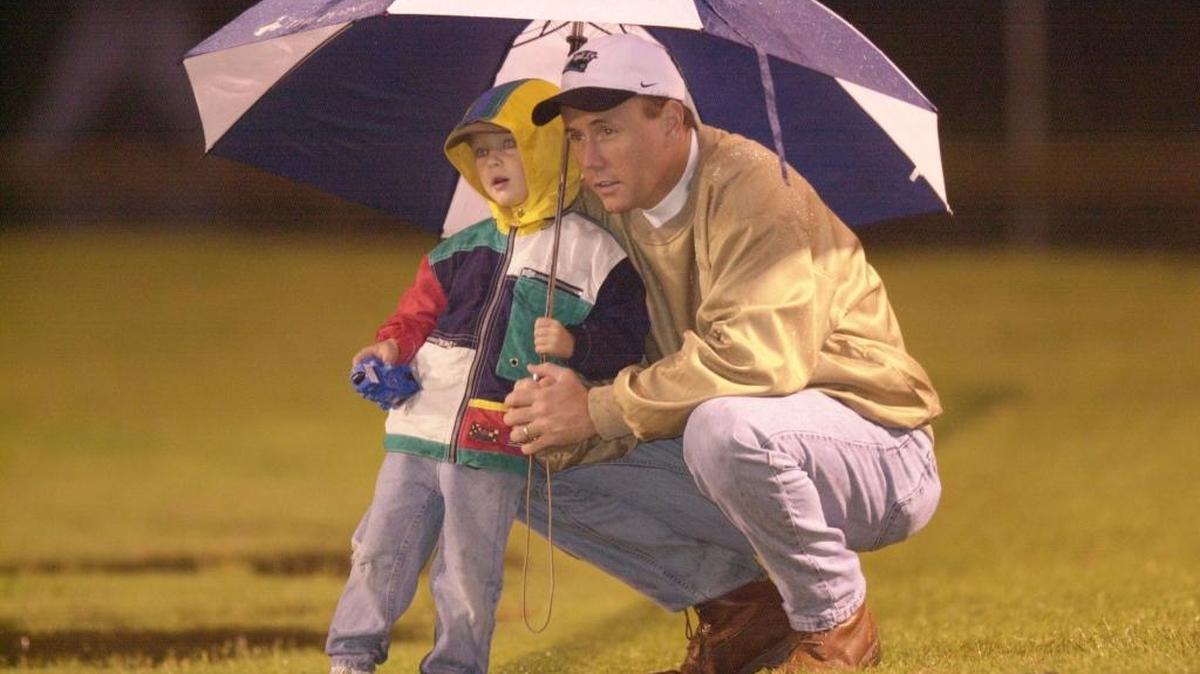 Back in 2002, Ryan Conner, 3, and his father Pat Conner watch the football game between Providence High School and Independence in the rain. More rainy weather is expected in the area this weekend, and some schools are moving games up