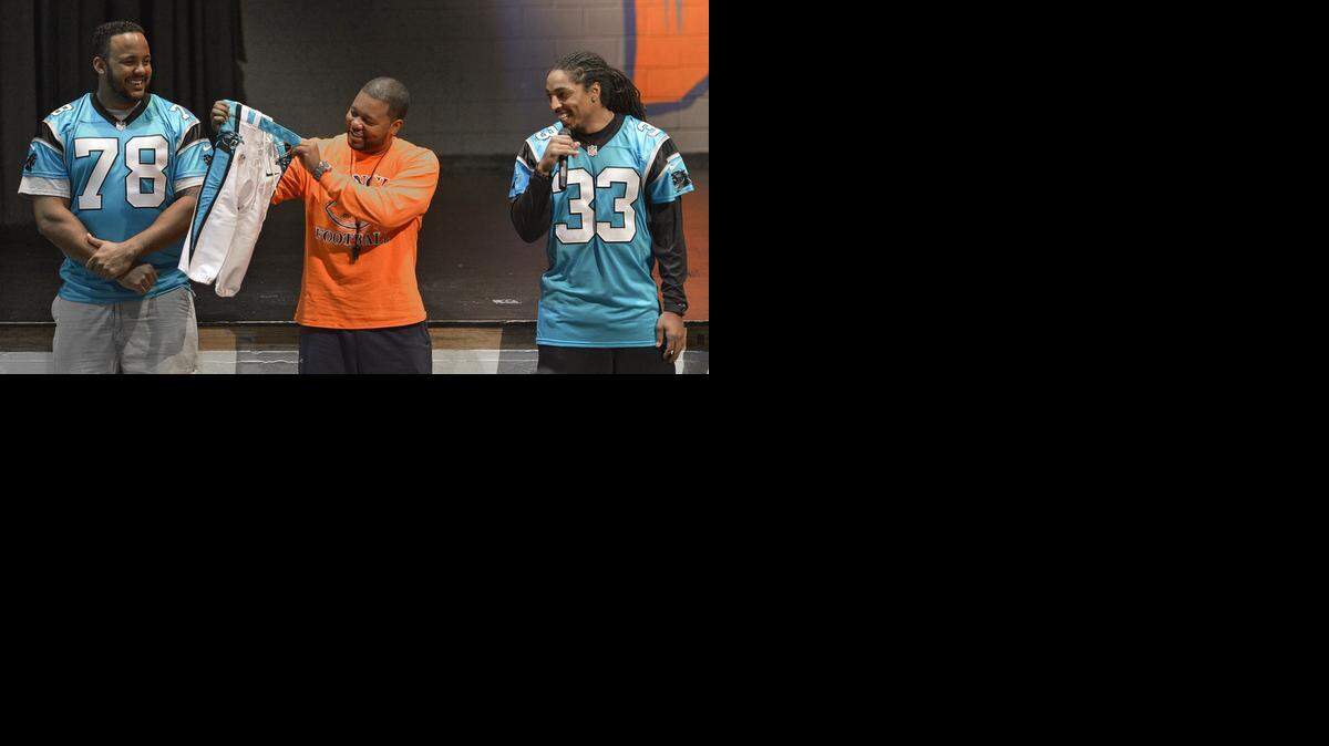 
Carolina Panthers Nate Chandler (78) and Tre Boston (33) have fun with Vance football coach Aaron Brand as they present him with a pair of Panther game pants. As part of the Carolina Panthers High School Uniform Grant program, safety Boston, offensive tackle Chandler and kicker Graham Gano presented the Vance High School football team with authentic Carolina Panthers game pants. 
