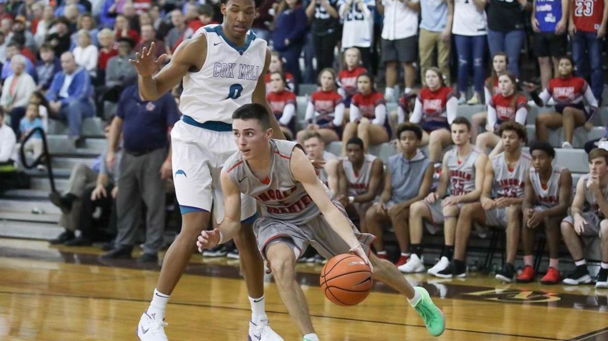 Lincoln Charter's Kody Shubert (center) drives the baseline during late first half action. Cox Mill and Wendell Moore (right) won the showdown between reigning NCHSAA state champions Wednesday