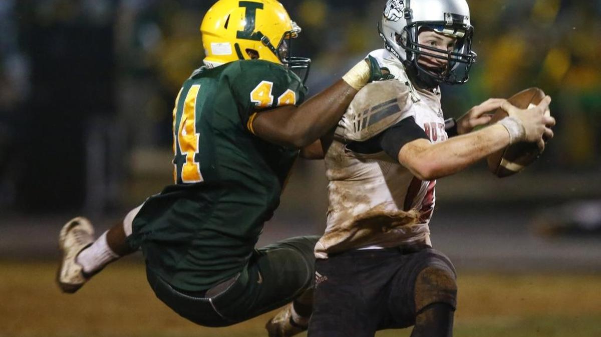 Independence defender Tylon Claswon (44) wraps up Butler quarterback Davis Cheek during the Southwestern 4A championship prep football game at Independence High Friday. Both teams begin N.C. playoff play Friday Photo by JASON E. MICZEK - Special to the Observer