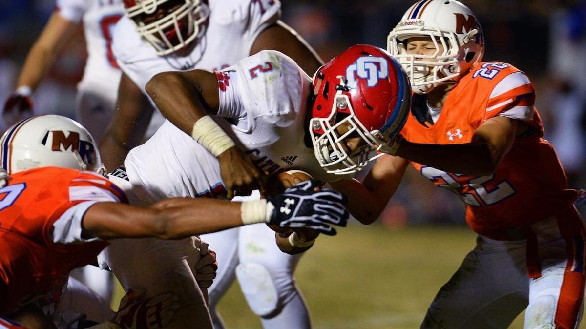 Charlotte Catholic running back Milan Howard, center, lowers his shoulder as he rushes for yardage against Marvin Ridge during the first quarter of Friday’s game.