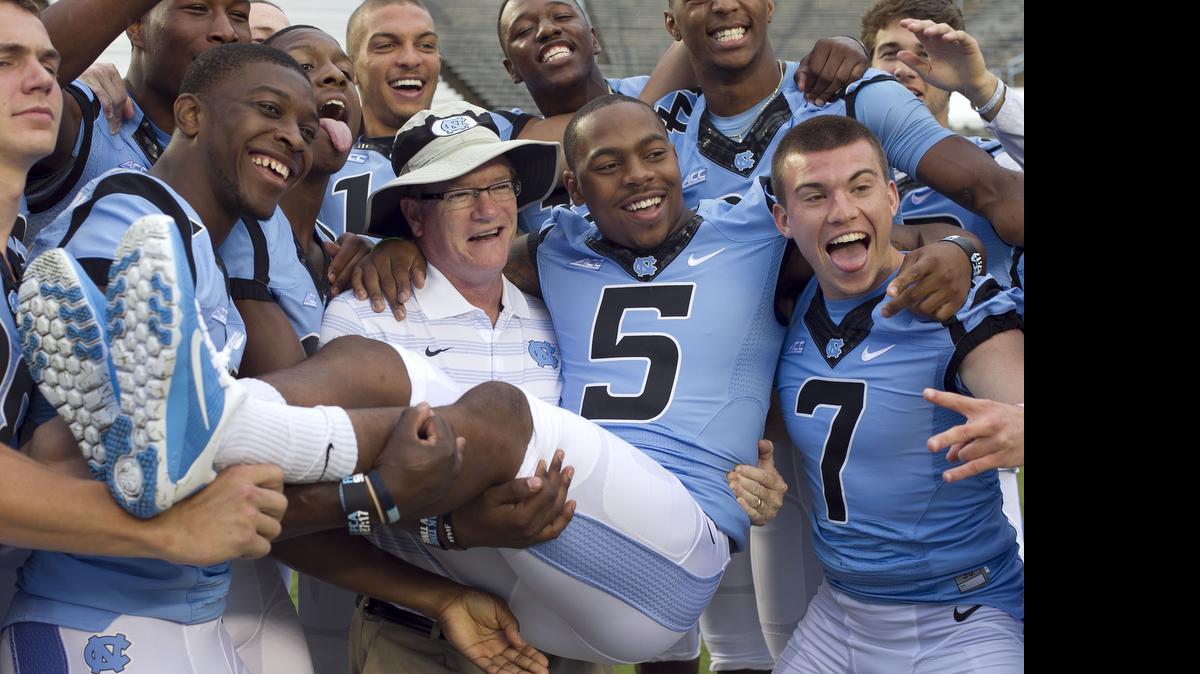
UNC assistant coach Gunter Brewer poses for a fun photograph holding receiver T.J. Thorpe (5) in his arms during the Tar Heels' media day on Saturday, August 2, 2014 at Kenan Stadium in Chapel Hill, N.C.
