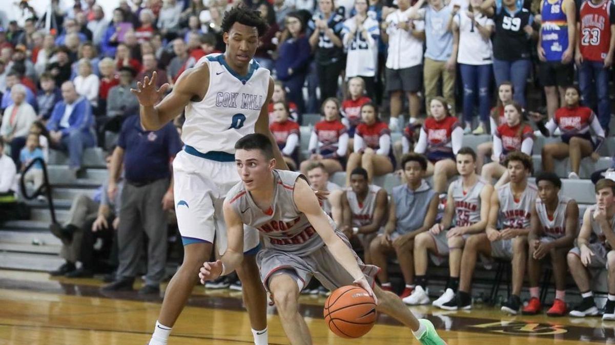 Lincoln Charter's Kody Shubert (center) drives the baseline during late first half action. Cox Mill and Wendell Moore (right) won the showdown between reigning NCHSAA state champions Wednesday