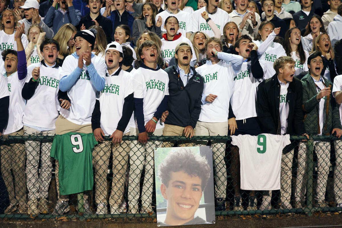 Myers Park High School students cheer at the NCHSAA boys' soccer quarterfinals alongside a large photo of Parker South, a student at the school who died on Tuesday, Nov. 11, 2025.