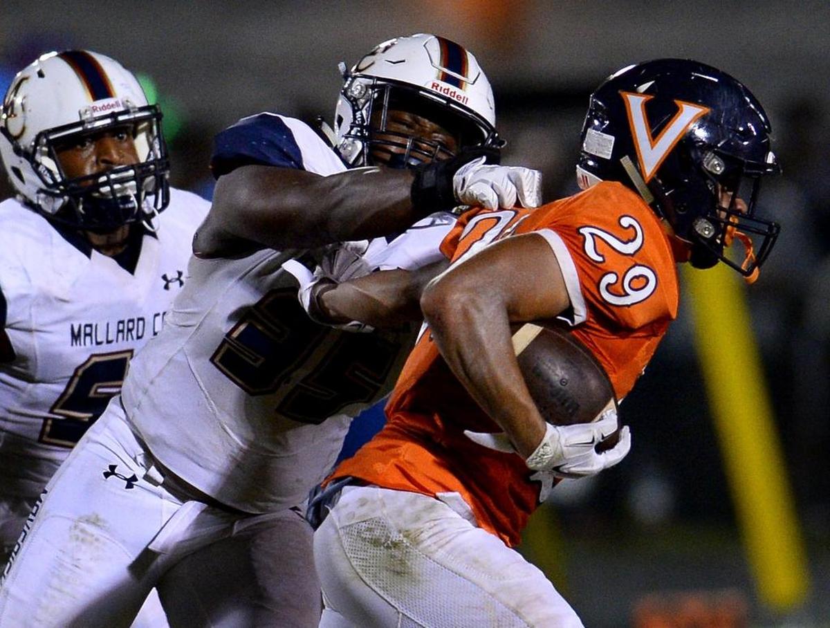 Mallard Creek linebacker Kalen Allen, center, makes the tackle on Vance running back Kalen Clark, right, during second quarter action on Friday, September 22, 2017 at Vance High School.