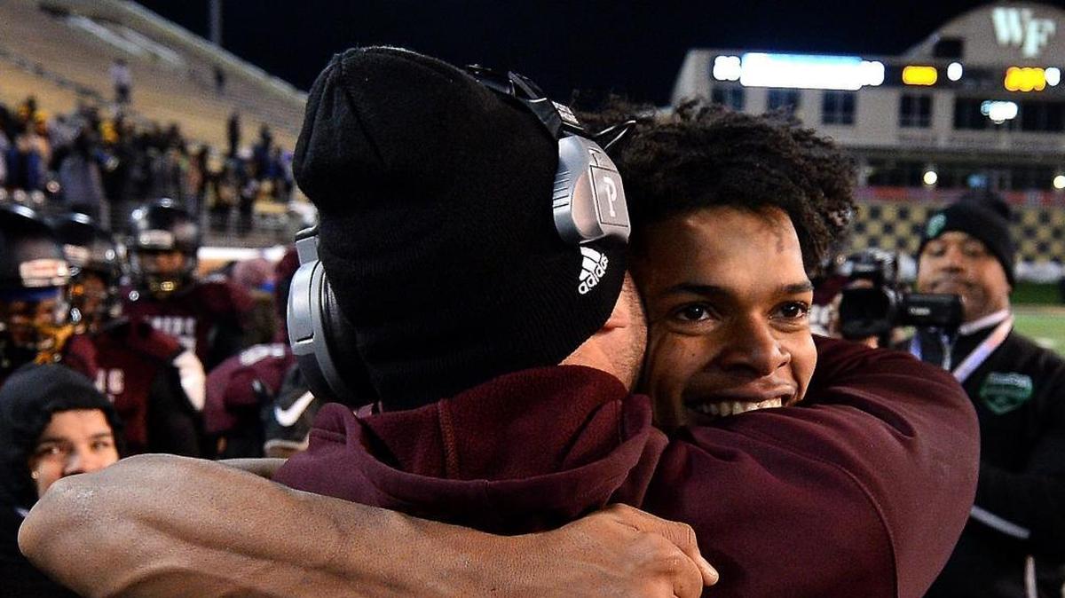 Harding University head coach Sam Greiner, left and quarterback Braheam Murphy, right, embrace along the team's sideline after Murphy ran for a 95-yard touchdown against Scotland County during fourth quarter action in the NCHSAA 4A State Championship game at BB&T Field in Winston-Salem, NC on Saturday, December 9, 2017. Harding defeated Scotland County 30-22.