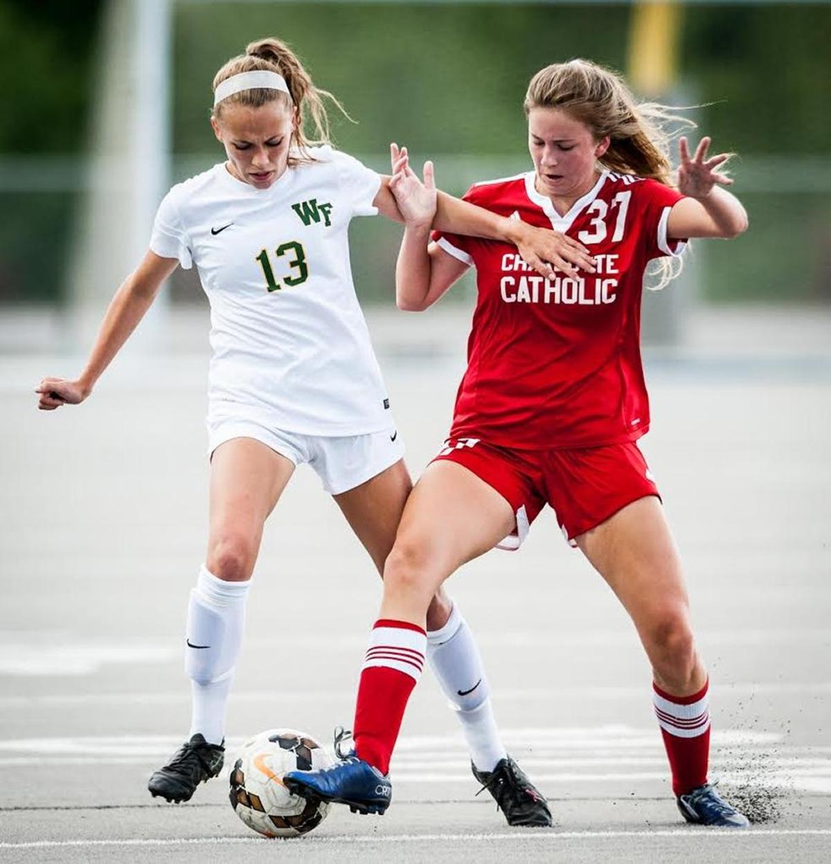 West Forsyth junior Erin Blevins (13) and Charlotte Catholic junior Lindsey Poff (37) vie for possession of the ball in the NCHSAA Class 4-A girls semifinal soccer game Thursday evening, May 25, 2017 at Pine Lake Prep Athletic Complex in Mooresville, N.C. The Titans defeated the Cougars, 4-3, in penalty kicks.(Winston-Salem Journal/Allison Lee Isley)20170526w_spt_catholicwestsoccer