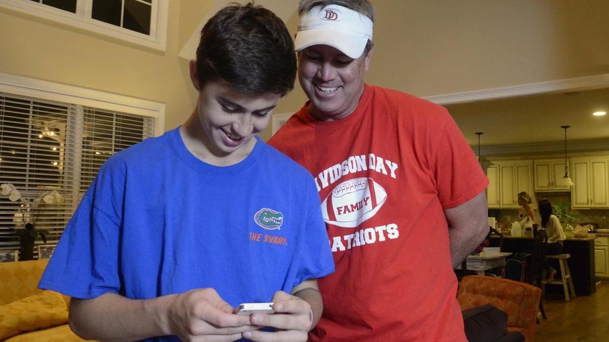 
Nash Grier, left, then 15, and his dad Chad Grier look over the Vine video clip Nash just shot "stair diving part 2" where Nash and his brother Hayes slide down the stairs in a plastic swimming pool landing at the bottom of the stairs. 
