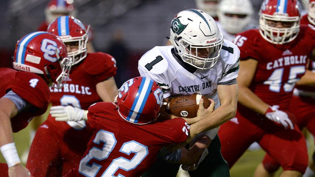 Charlotte Catholic's Rob Dumser, center/left, looks to make the tackle on Charlotte Country Day quarterback Wes Bingham, center/right, on a run during first quarter action on Friday, September 2, 2016.