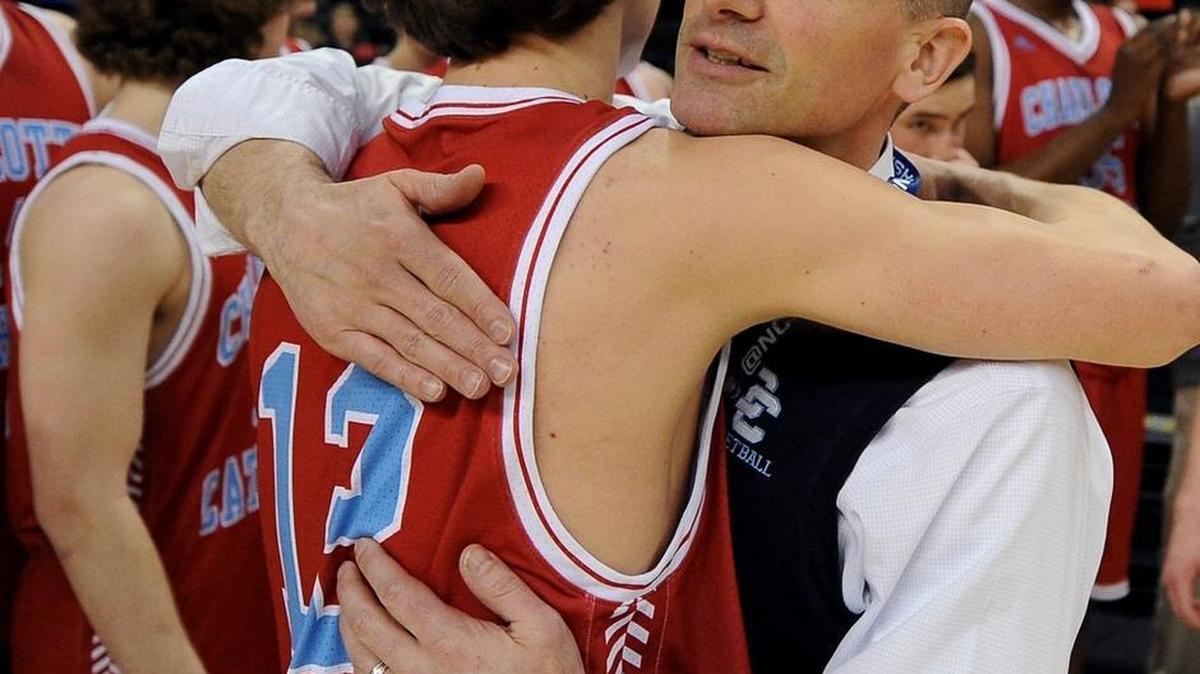 Charlotte Catholic boys’ basketball coach Mike King, left, hugs Sam Smith after the Cougars’ 46-41 win against North Mecklenburg last Saturday in the N.C. 4A Western Regional championship game in Winston-Salem. Catholic will play Cary in Chapel Hill on Saturday for the state championship.