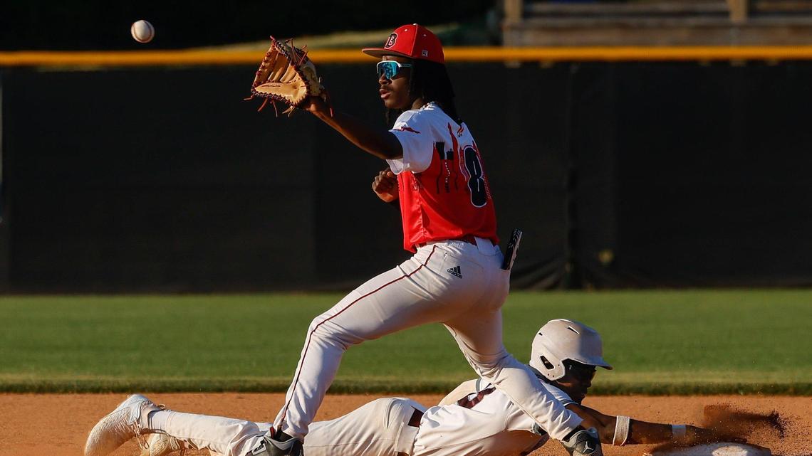 West Meck’s Godeson Hakim, bottom, slides safely back to first base as the ball is thrown to Phillip O. Berry’s first baseman Caden Briscoe during the championship game between Phillip O. Berry Academy of Technology and West Mecklenburg High School at Richard “Stick” Williams” Dream Fields and Education Center in west Charlotte on Tuesday, April 15, 2025.