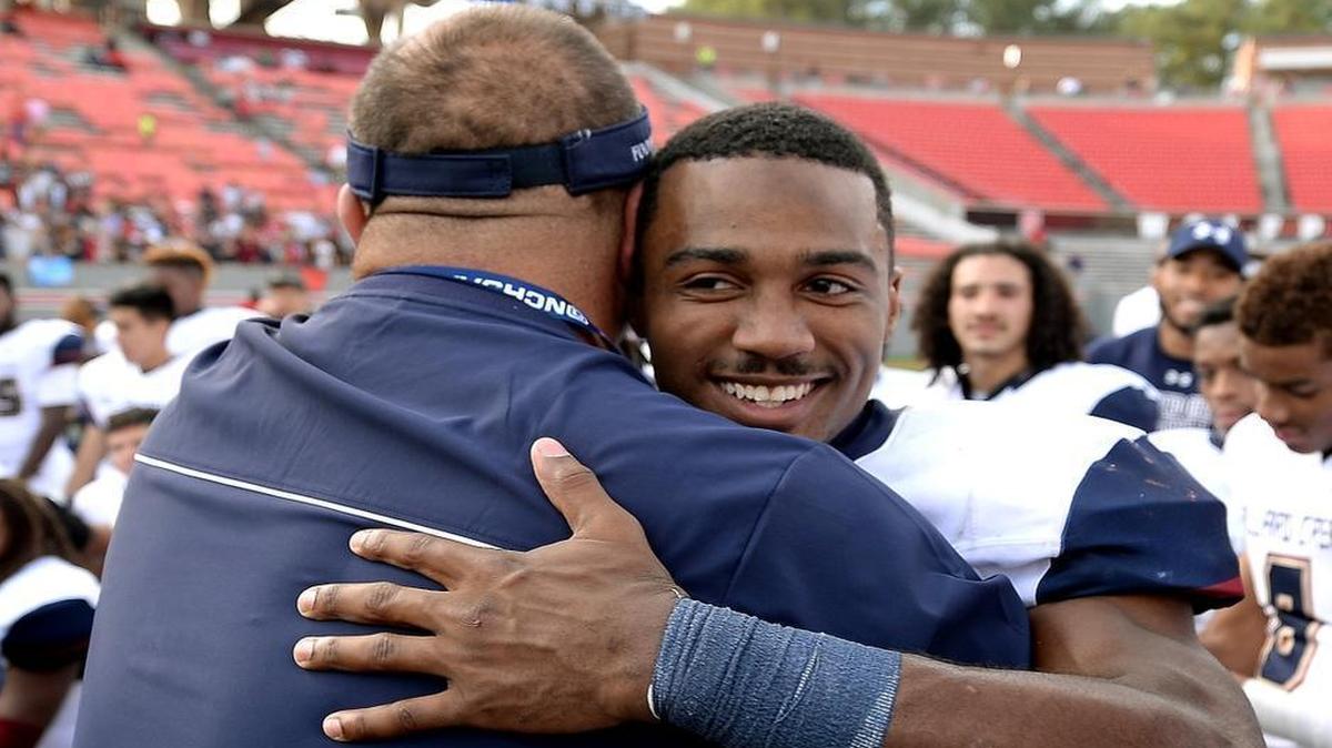 Mallard Creek Mavericks head coach Mike Palmieri, left, hugs quarterback James Smith, the Charlotte Observer offensive player of the year, following the team's victory over Page at Carter-Finley Stadium in Raleigh, NC on Saturday, December 12, 2015. Mallard Creek defeated Page 49-6 to win the NC 4-AA Championship.