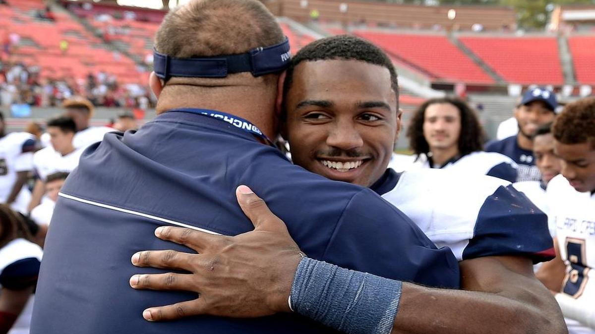 Mallard Creek Mavericks head coach Mike Palmieri, left, hugs quarterback James Smith, right, following the team's victory over Page at Carter-Finley Stadium in Raleigh, NC on Saturday, December 12, 2015. Mallard Creek defeated Page 49-6 to win the NC 4-AA Championship.