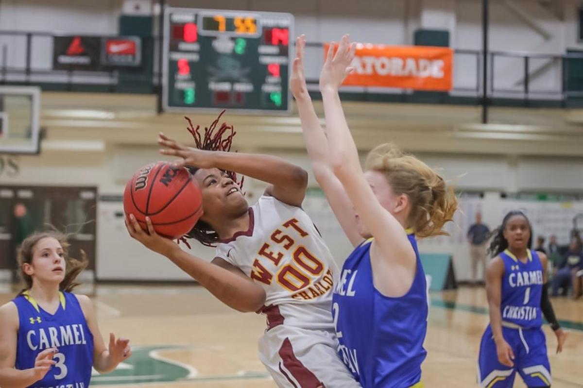 Junior D'Nya Hamilton (00) of West Charlotte goes to the basket strong and attempts a shot against a Carmel Christian defender.