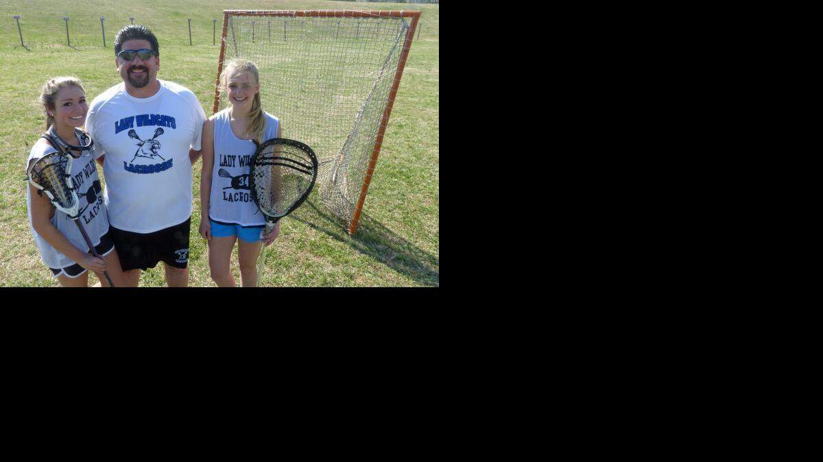 
Lake Norman High girls’ lacrosse coach Chris Schiemer, center, stands with junior midfielder Carly Vaccaro, left, and sophomore goalkeeper Korina Kempthorn at the Wildcats’ practice field. Lake Norman is off to a 7-0 start, including victories over two defending state champions and a regional champion. 
