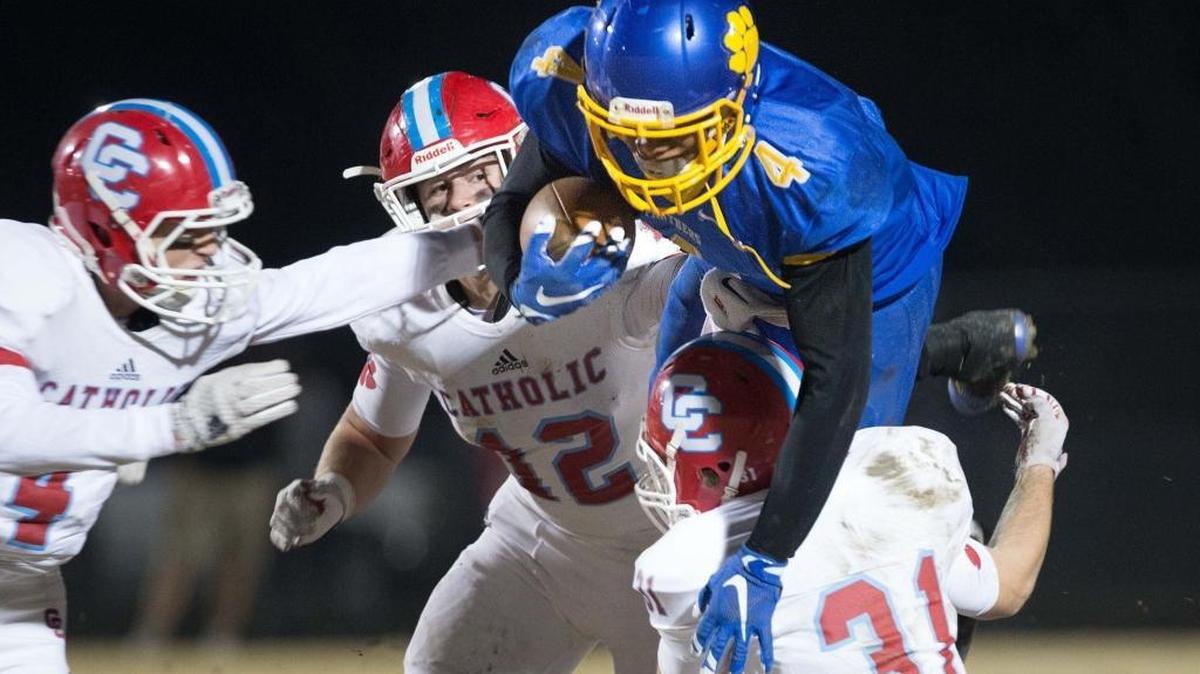 Dudley's Simeon Gatling (4) goes over Charlotte Catholicâ€™s Andrew Brouse (31) on the carry with Charlotte's Benjamin Brodowicz (4) and Alexander Gagnon (12) trying for the stop as Dudley plays Charlotte Catholic for the 4-A West Regional football championship on Friday, Dec. 4, 2015, in Greensboro, N.C. (Lynn Hey/News & Record)