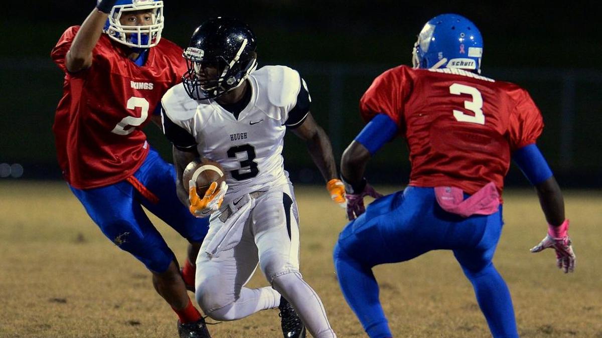 Hough wide receiver Marquill Osborne, center, breaks between North Meck defensive lineman Tre Turner, left, and defensive back De'Montrez Burroughs, right, during first-quarter action on Friday at North Meck High.