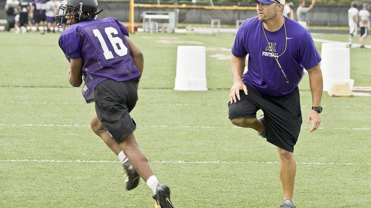 
Knights head coach Joe Evans, right, pulls his leg out of the way as junior running back DeCareio Gibbs, left, makes a cut while doing a passing drill during the Ardrey Kell High School football practice.
