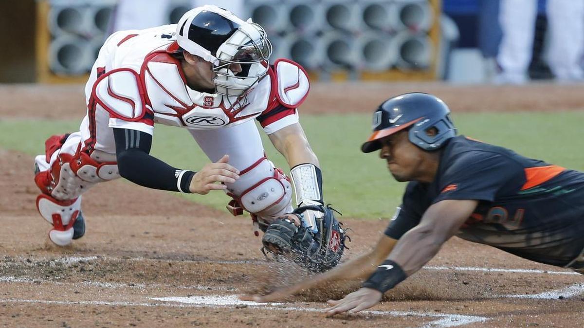 
Miami's Ricky Eusebio (2) slides under the tag by N.C. State's Andrew Knizner (11) and scores on a sacrifice fly in the third inning  in the ACC Baseball Tournament at the Durham Bulls Athletic Park in Durham.
