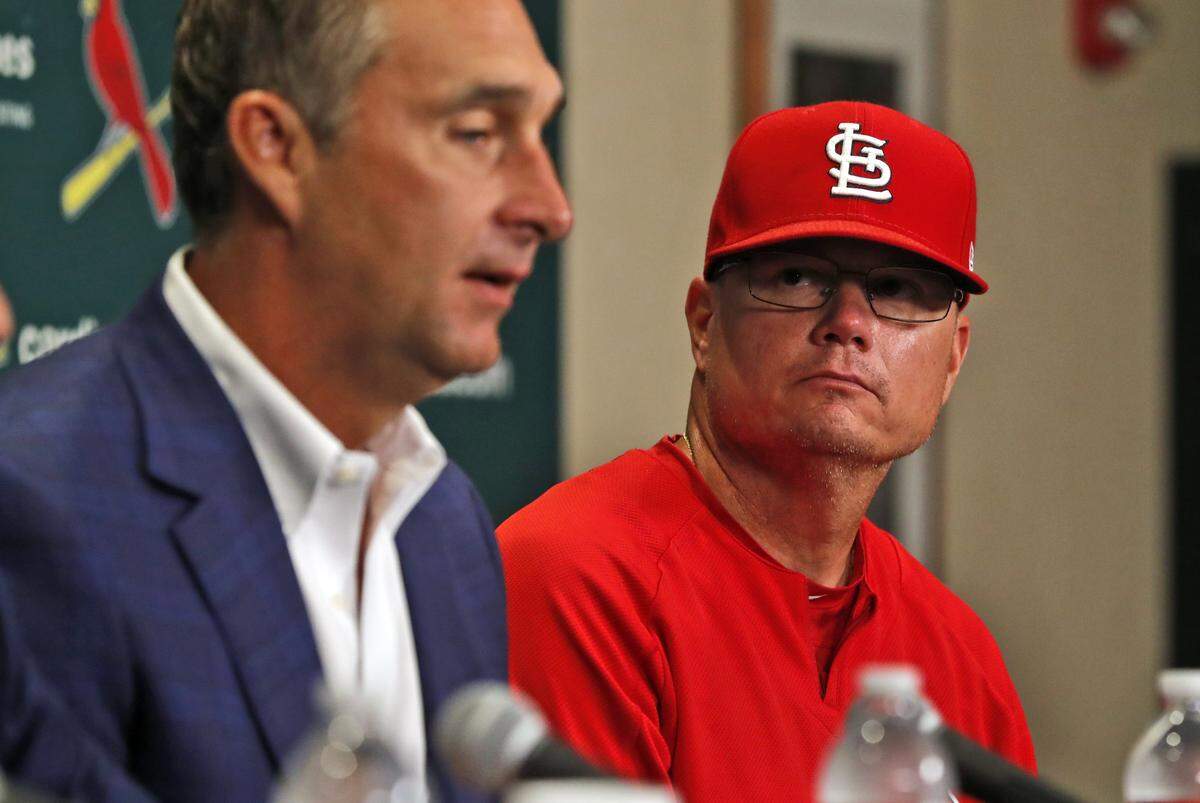 St. Louis Cardinals president of baseball operations John Mozeliak, left, speaks about the firing of Cardinals manager Mike Matheny as interim manager Mike Shildt, right, listens before a baseball game between the Cardinals and Cincinnati Reds Sunday, July 15, 2018, in St. Louis. The Cardinals fired Matheny after an 8-2 loss to the Reds on Saturday night with the team hovering around .500. (AP Photo/Jeff Roberson)
