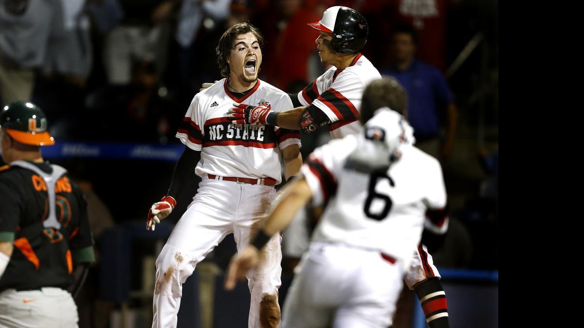 
N.C. State's Preston Palmeiro (12), center, celebrates after scoring in the 12th inning during N.C. State's 5-4 victory over Miami in 12 innings in the ACC Baseball Tournament at the Durham Bulls Athletic Park in Durham, N.C., Friday, May 22, 2015.
