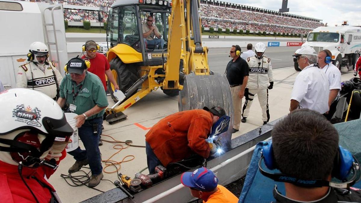 
Pocono Raceway officials work to repair a section of the pit wall damaged in an on-track incident involving Kasey Kahne in Sunday’s Windows 10 400.
