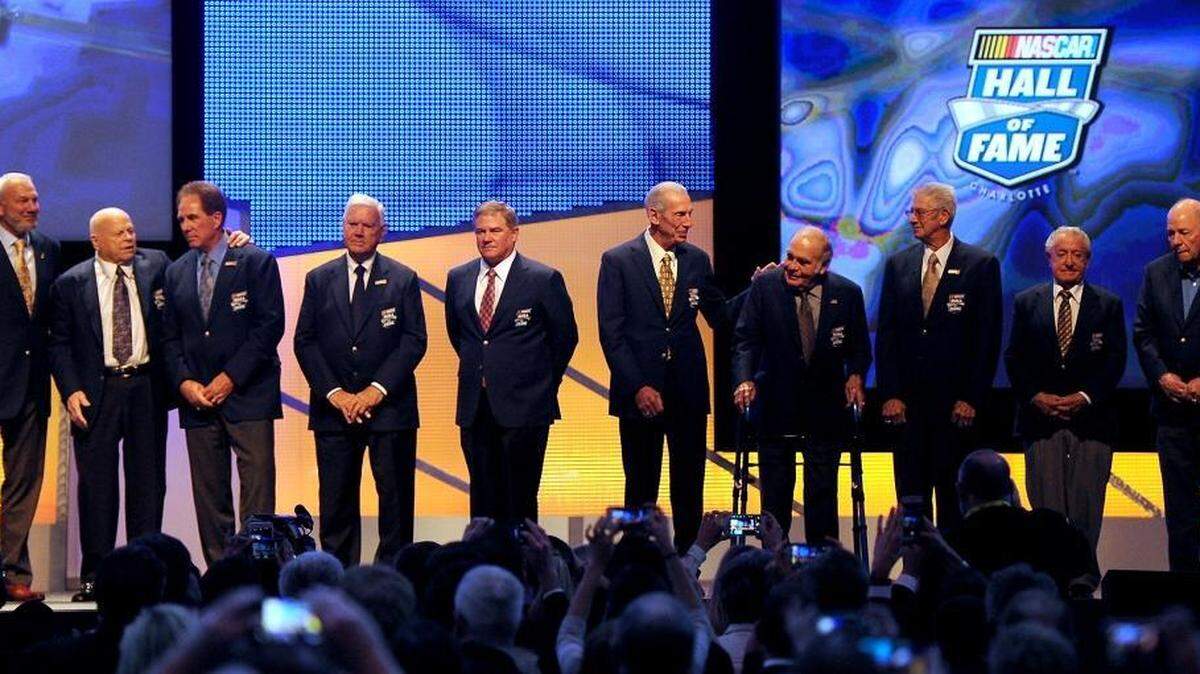 NASCAR Hall of Fame members, from left, Dale Jarrett, Bruton Smith, Darrell Waltrip, Junior Johnson, Terry Labonte, Ned Jarrett, Jerry Cook, Leonard Wood, Rex White and Jack Ingram pose on the stage following the NASCAR Hall of Fame Induction Ceremony on Saturday.