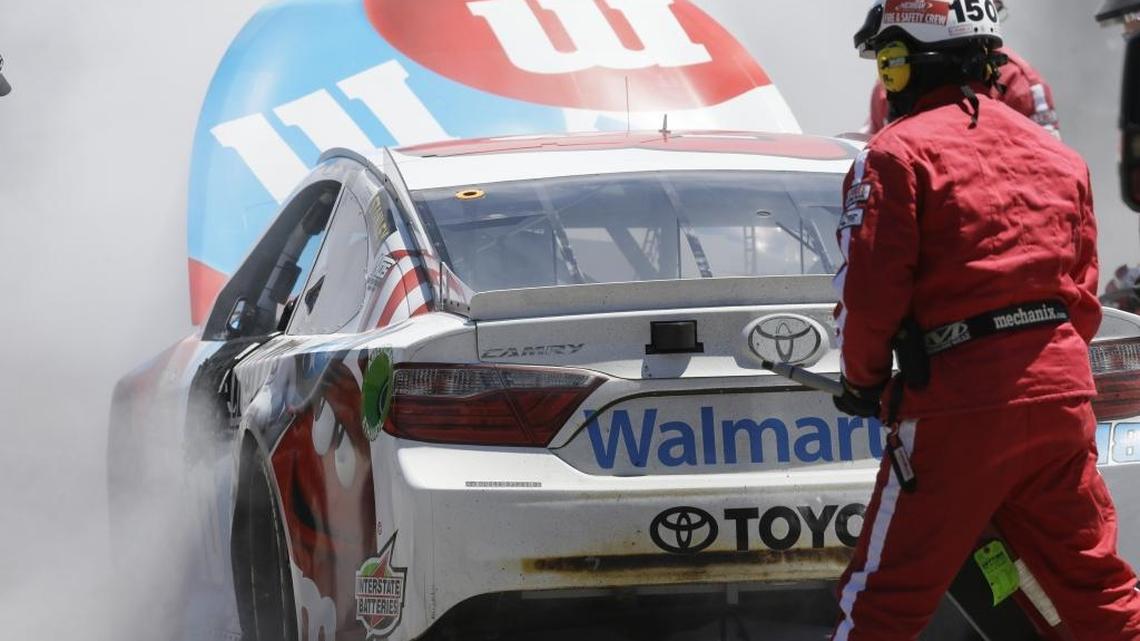 Safety crews extinguish the fire in Kyle Busch’s car in the garage at Michigan International Speedway on Sunday.