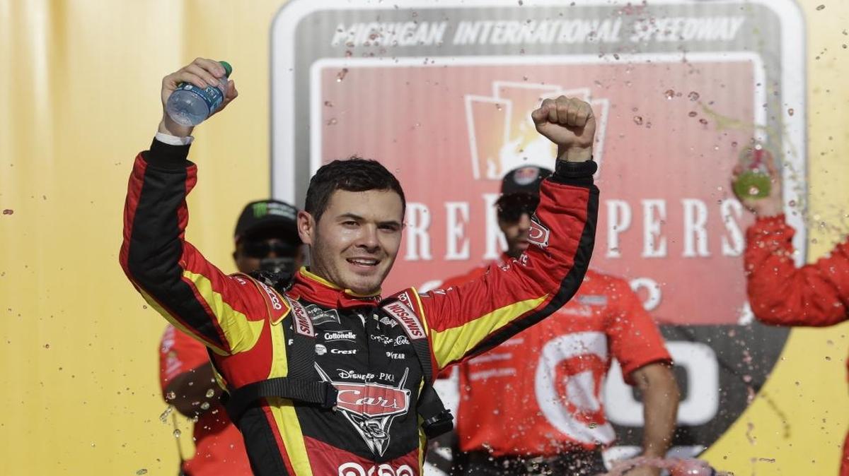 Kyle Larson raises his arms after exiting his car after winning Sunday’s NASCAR Sprint Cup series auto race in Brooklyn, Mich.