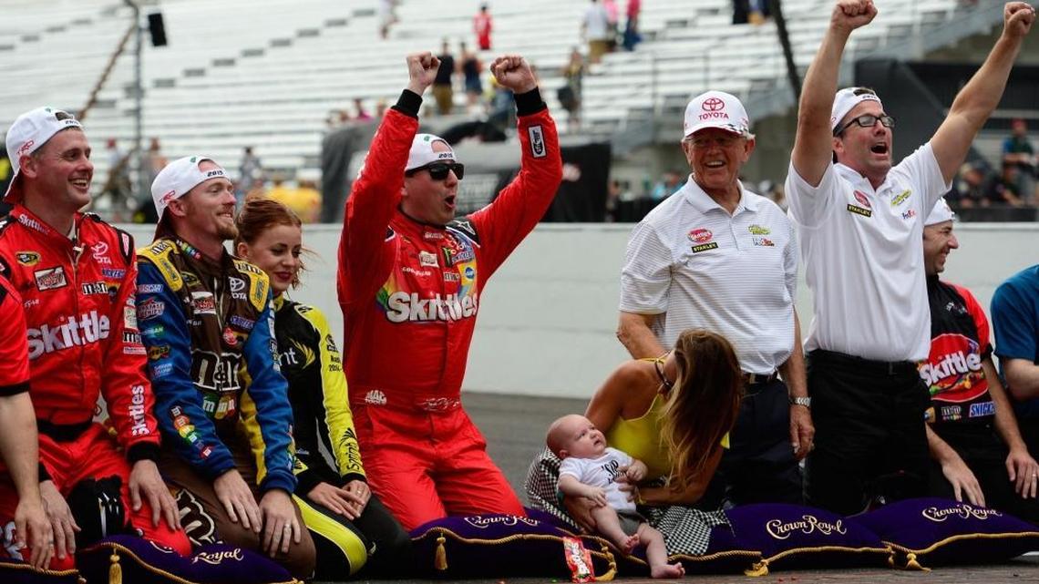 Kyle Busch celebrates with his wife Samantha and their son Brexton by kissing the bricks after winning the Sprint Cup race at Indianapolis Motor Speedway on July 26, 2015.