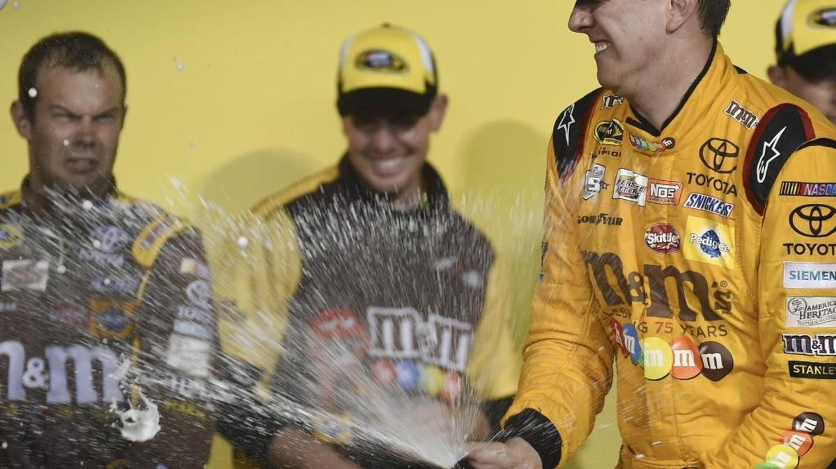 Kyle Busch (right) celebrates after winning last week’s race at Kansas. Crew chief Adam Stevens was penalized for lug-nut infraction announced Wednesday.