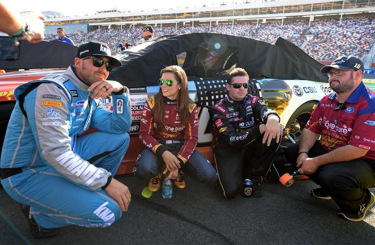 NASCAR drivers Paul Menard, left, Danica Patrick and crew members wait along pit road for the NASCAR Monster Energy Open to begin on Saturday at Charlotte Motor Speedway.