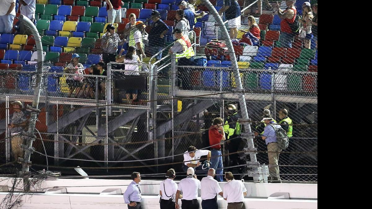 
Track officials confer at the site of impact at the catch fence, after the mutlicar crash at the finish of the Coke Zero 400 at Daytona International Speedway early Monday morning.

