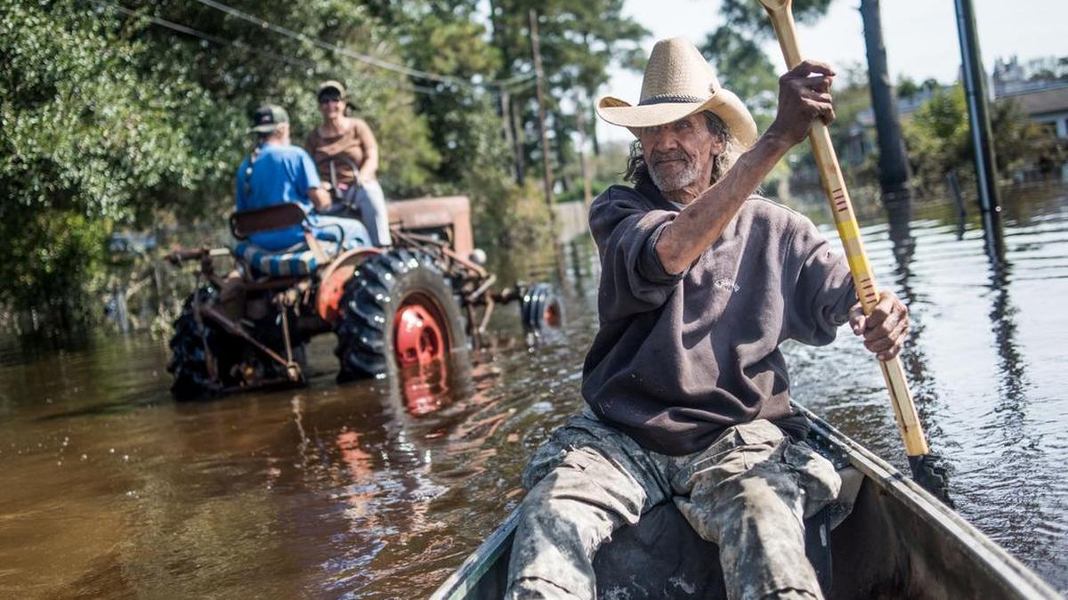 Harvey Wearnes paddles a canoe through a flooded street in his neighborhood in Lumberton on Oct. 15. The flooding caused by Hurricane Matthew caused 26 deaths in the state.