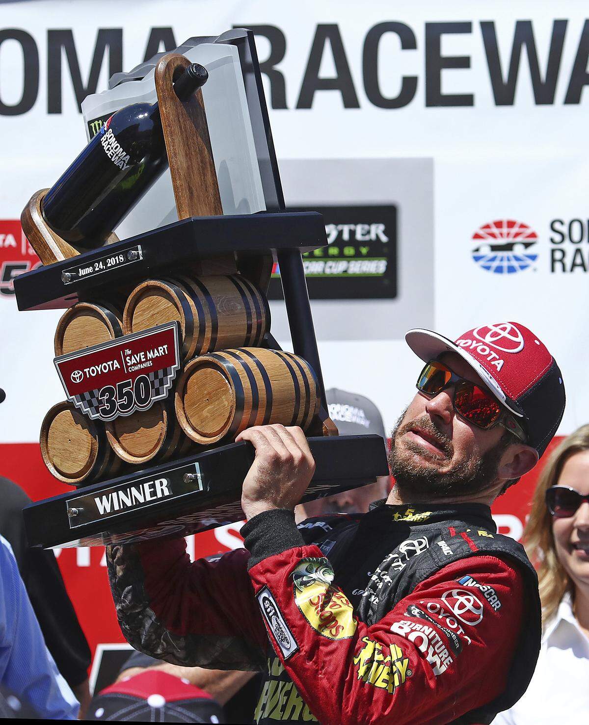 Martin Truex Jr. raises the trophy after winning a NASCAR Sprint Cup Series auto race Sunday, June 24, 2018, in Sonoma, Calif. (AP Photo/Ben Margot)