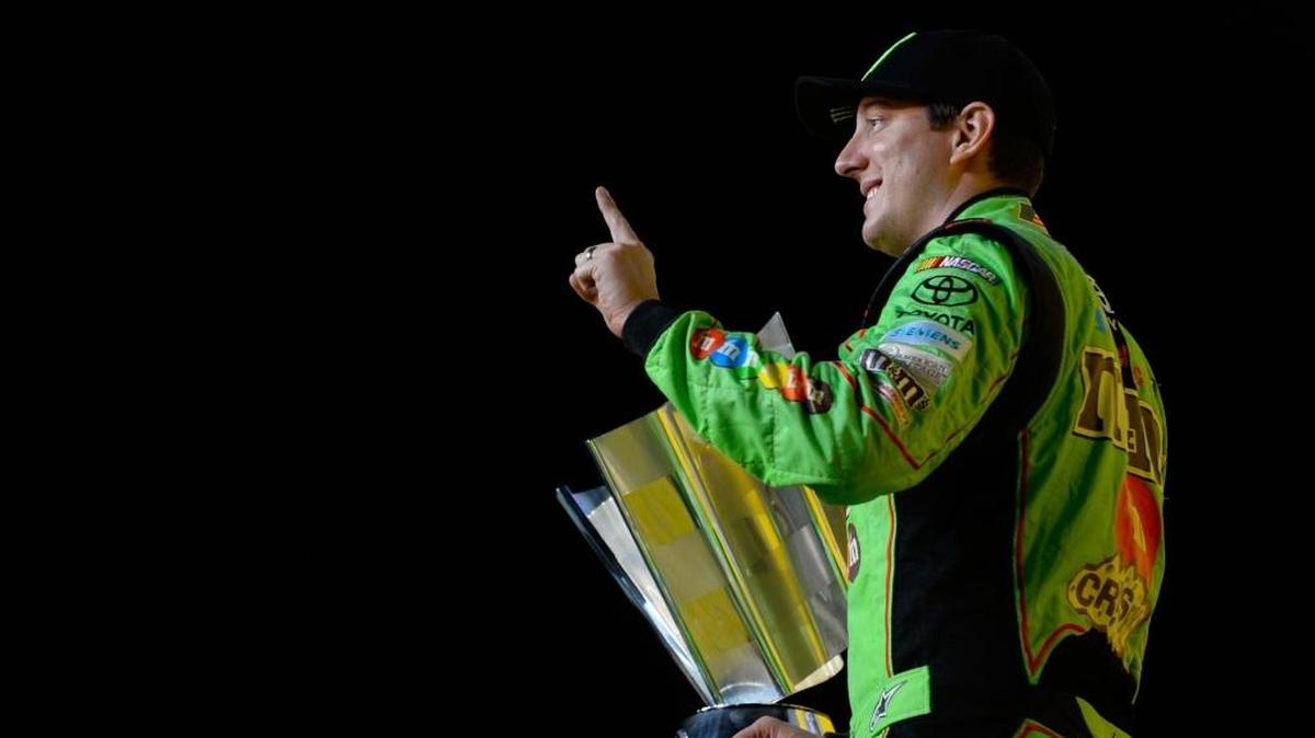 Kyle Busch, driver of the #18 M&M's Crispy Toyota, holds the trophy after winning the NASCAR Sprint Cup Series Ford EcoBoost 400.