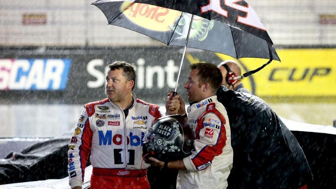 Tony Stewart, left, driver of the No. 14 Haas Automation Chevrolet, stands in the rain during the NASCAR Sprint Cup Series Bass Pro Shops NRA Night Race at Bristol Motor Speedway on August 20, 2016 in Bristol, Tennessee.