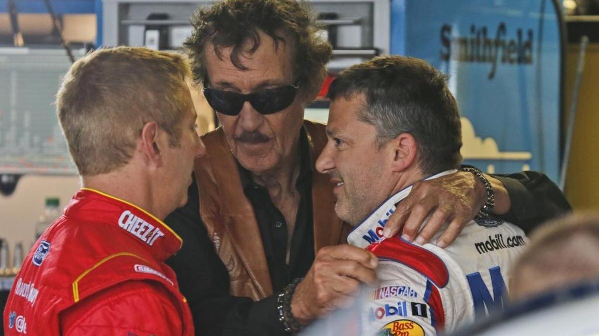 Richard Petty, center, hugs Tony Stewart in the garage as they talk to Greg Biffle, left, after a first round of practice for Sunday's NASCAR Sprint Cup auto race at Richmond International Raceway in Richmond, Va., Friday. Stewart is making his return to Sprint Cup racing after a preseason injury.