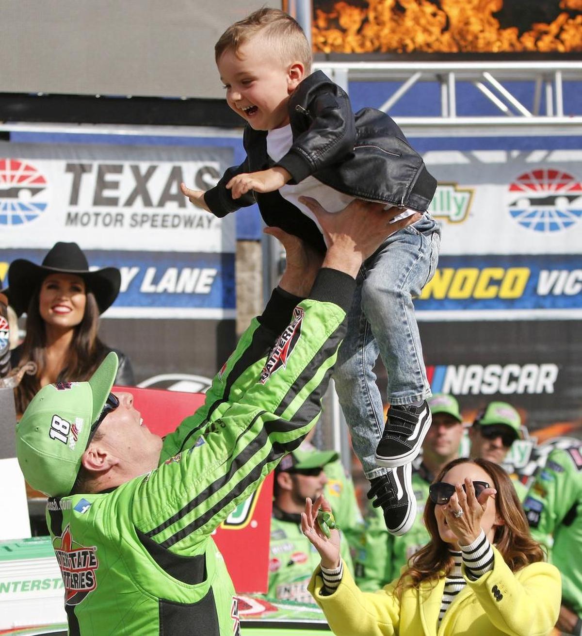 Kyle Busch (18) plays with his son Brexton as his wife, Samantha, offers support after he won Sunday’s O'Reilly Auto Parts 500 at Texas Motor Speedway.