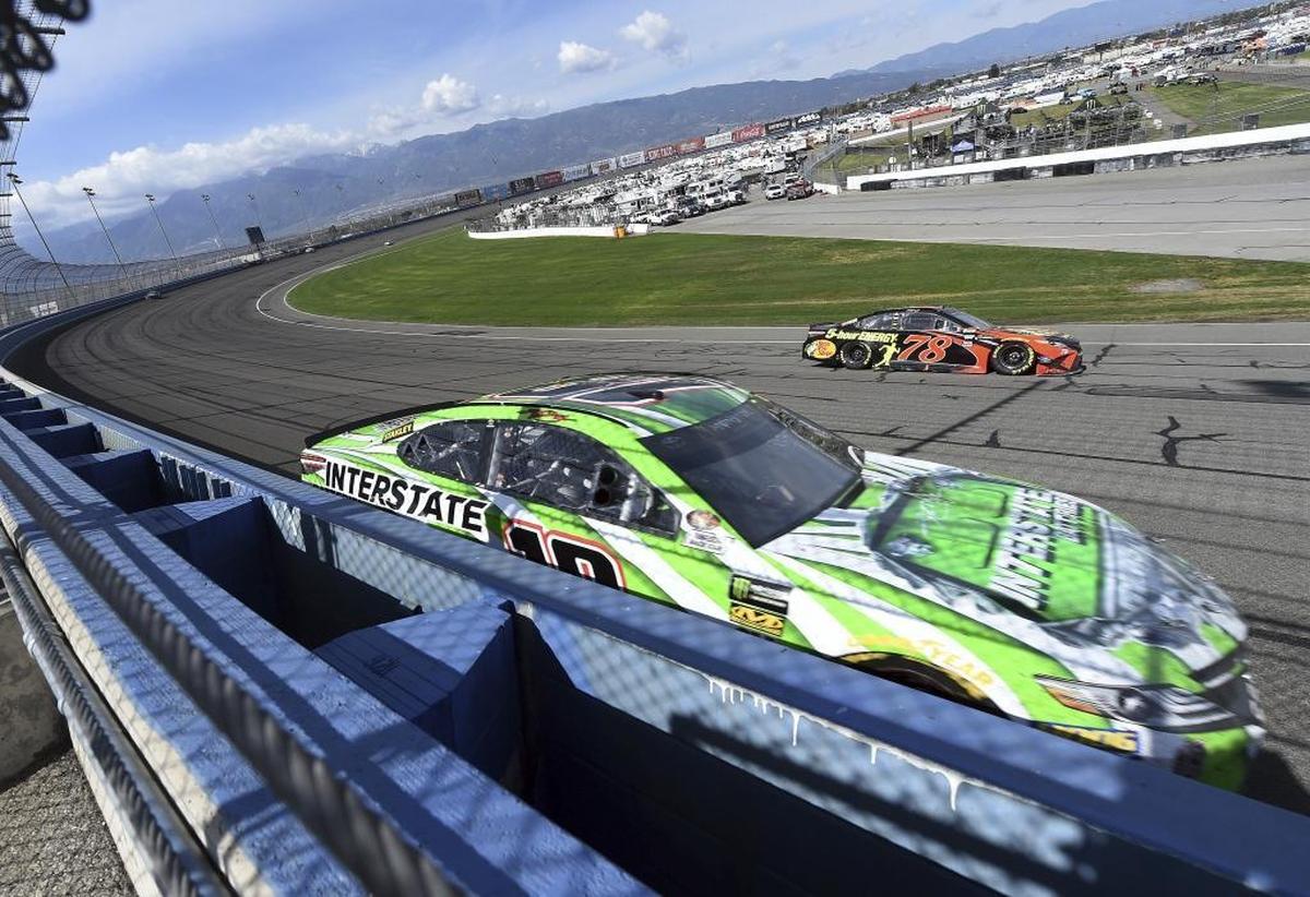 Defending NASCAR Cup Series champion Martin Truex Jr., background, passes Kyle Busch during the late laps of Sunday’s Auto Club 400 race at Auto Club Speedway in Fontana, Calif.