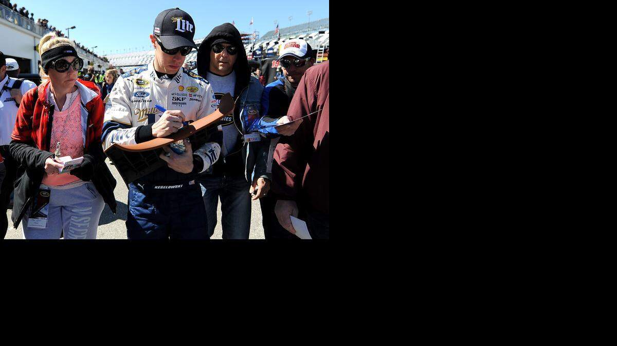 
Brad Keselowski signs autographs for fans as he walks to his hauler after practice Friday at Daytona. Keselowski was fourth fastest in the first session with a top speed of 192.279 mph.

