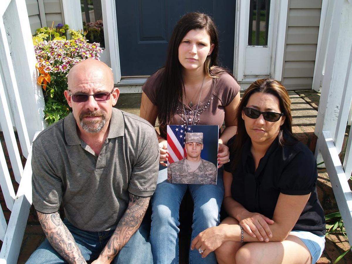 “It warms my heart to know that people are helping him not be forgotten,” Heather Barton, Christopher Barton’s widow, says. “That’s my biggest fear is people will just forget who he is.” Above, Heather Barton, center, holds Christopher Barton’s portrait in a 2010 photo with Christopher Barton’s parents, Roy and Elaine Schmiedeshoff.