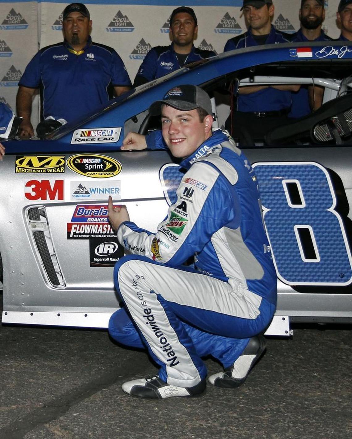 Alex Bowman points to the pole award sticker on his car after winning the pole for a Cup Series race at Phoenix International Raceway in November.